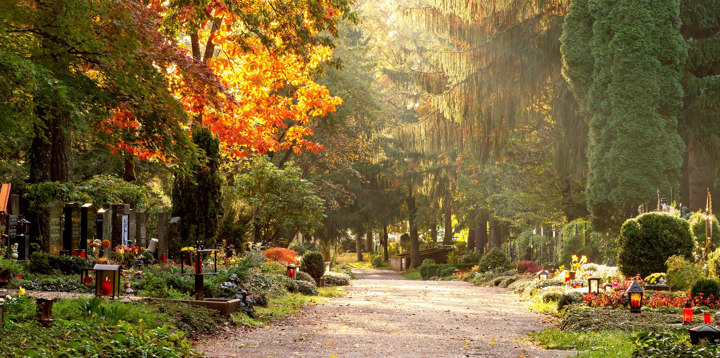 Weg, der über den Friedhof führt mit schön geschmückten Gräbern bei Herbst